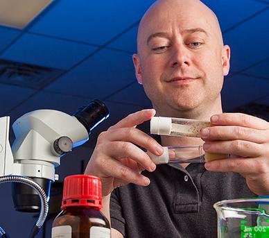 Professor Todd Blankenship examines test tube samples in a research lab.